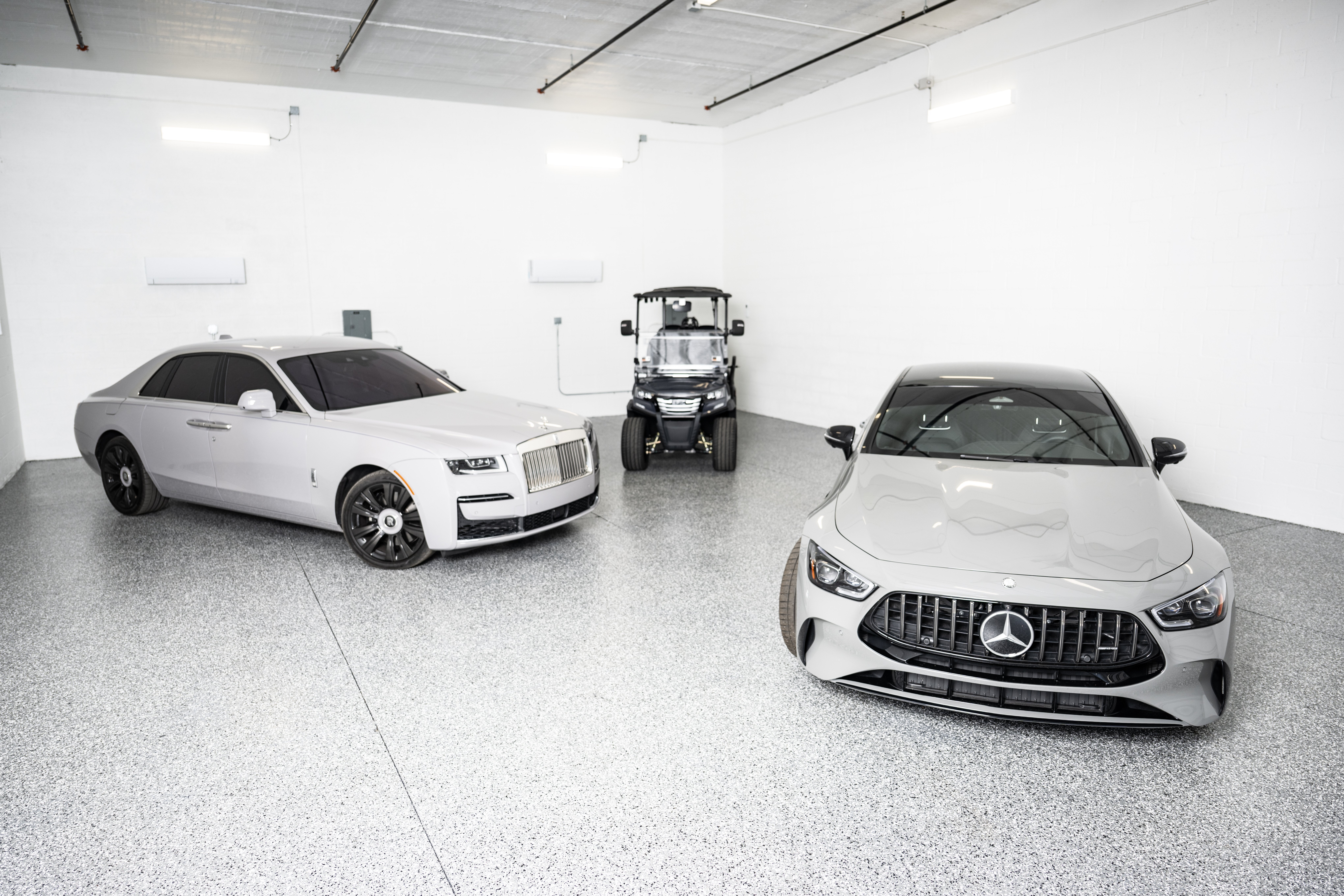 Two luxury vehicles and a utility cart stored inside a large private climate-controlled storage unit at MetroMaxx RV & Boat Storage in Fort Myers, Florida